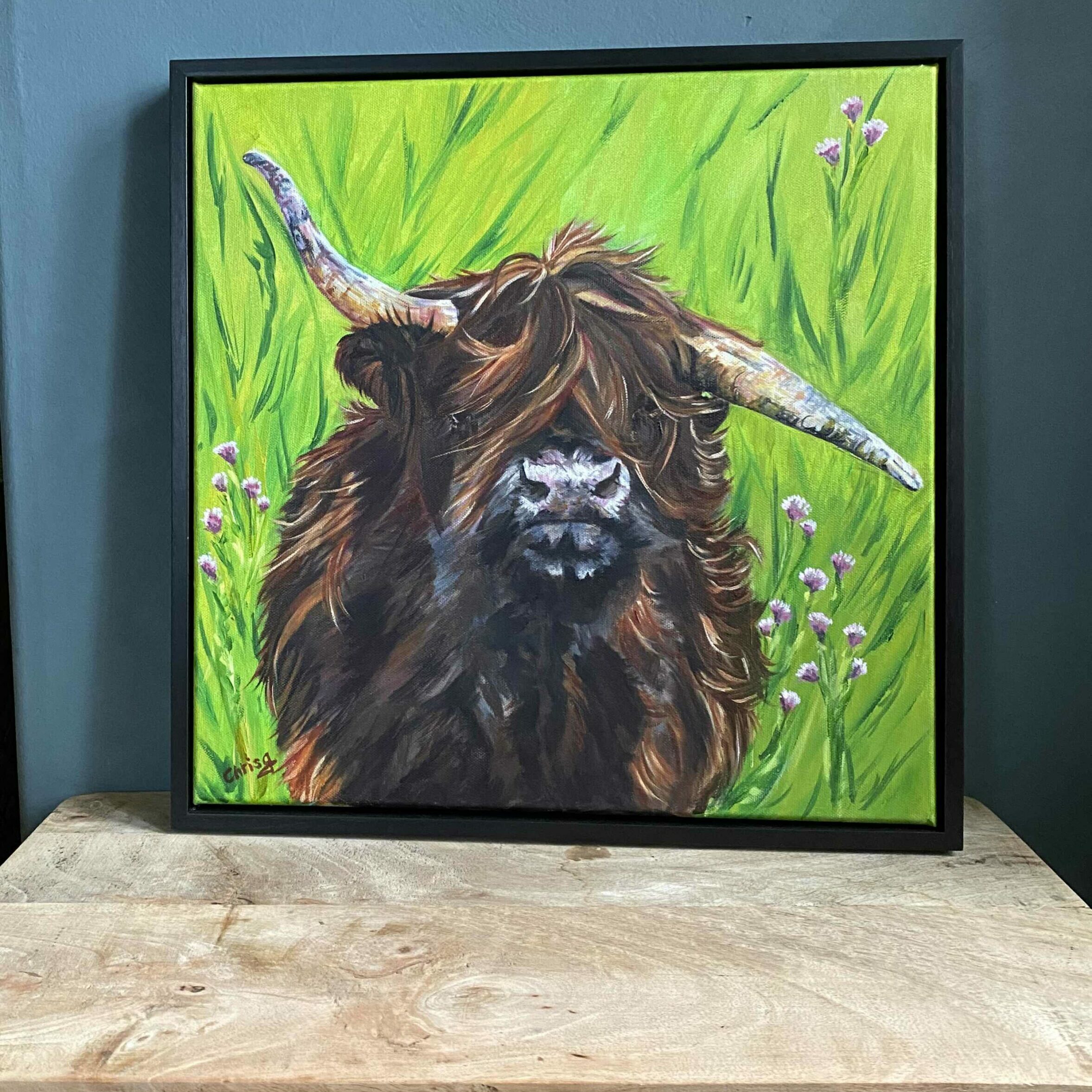 Brown Highland Cow on a Green leafy background. I call her my “wild child”. Not everyone is perfect but wild child’s horns point north and south it’s her imperfection but she’s beautiful and deserves a portrait.